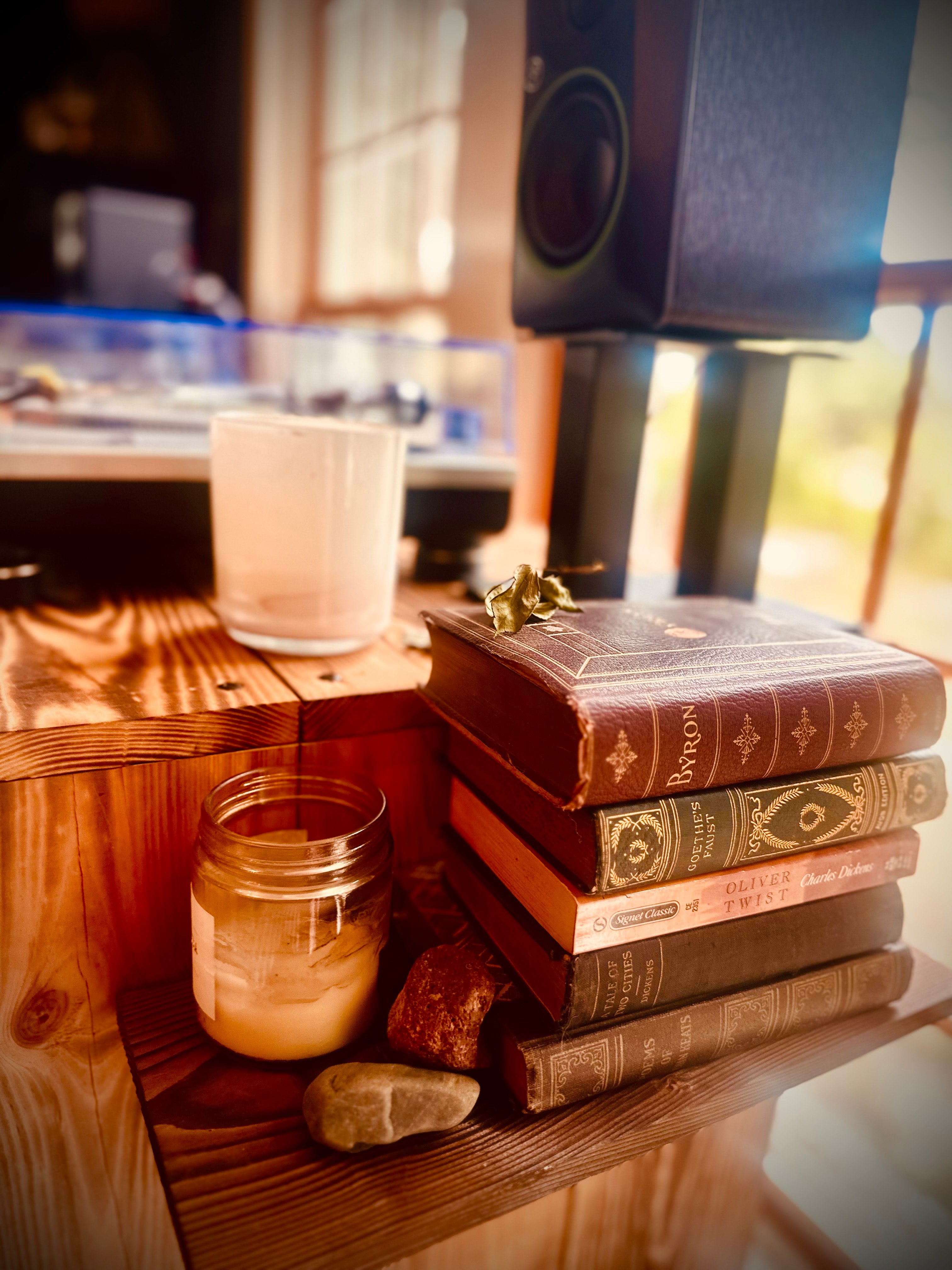 Stack of vintage books with candle and speaker